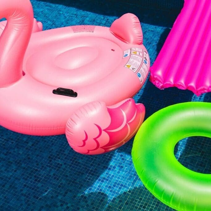 pink inflatable flamingo and green inflatable ring